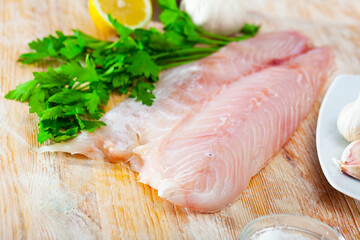 Fillet of fresh raw perch fish with greens on a wooden surface, nobody