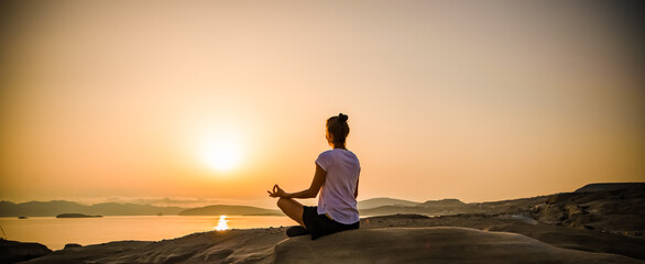 woman in white doing yoga and meditating by the sea