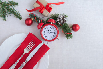 Christmas table setting with the red alarm clock on the white tablecloth. Top view. Copy space.