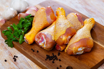Fresh chicken legs on wooden background with parsley and garlic
