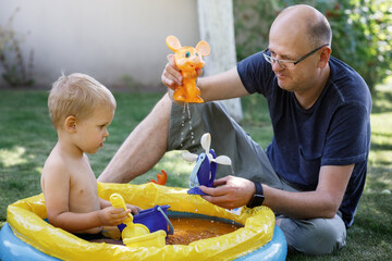 Grandchildren and grandfather playing with water toys.
