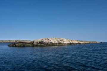 Fototapeta na wymiar A picture of a beautiful rock island. Ocean and blue sky in the background. Picture from the Weather Islands, on the Swedish West coast