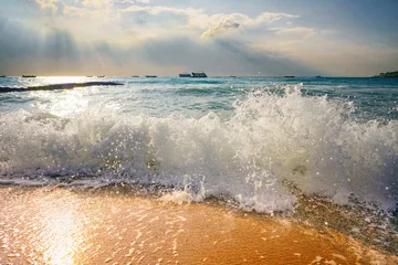 Schöne atmosphärische, natürliche, farbenfrohe Strandlandschaft mit Sonnenstrahlen, die bei Sonnenuntergang durch die Wolken scheinen. Tobende Wellen der Meeresbrandung im Sonnenlicht. © Laura Pashkevich