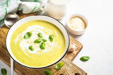 Zucchini soup with spinach and herb at white kitchen table.