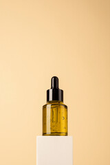 Naklejka premium Green glass dropper bottle with black lid on the white podium on biege background. Gel texture with bubbles in a container. Skincare products , natural cosmetic. Beauty concept for face and body care