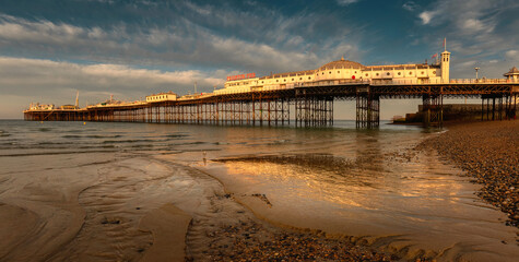 Brighton Pier in the morning sun with low tide sea and reflection, England