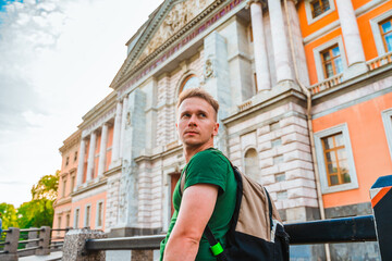 A young man in the center of St. Petersburg looks at the beautiful historical facade of the museum