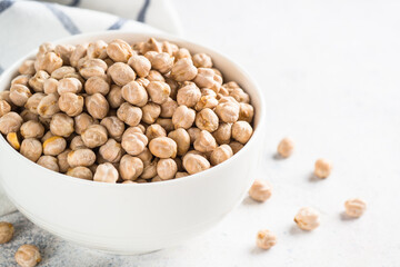 Chickpeas in white bowl at light kitchen table. Uncooked raw chickpea beans.