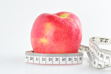 Close up, red apple with measuring tape, isolated on white background. Concept, healthy eating, keep the line.