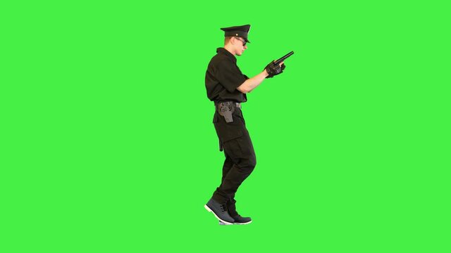 Policeman walks doing some exercices with his gun on a Green Screen, Chroma Key.