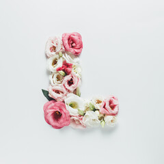 Obraz na płótnie Canvas Letter L made with flower and leaves on bright white background. Floral mother's day alphabet concept. Spring blossom, valentine or romantic font collection. Flat lay, top view.