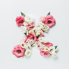 Obraz na płótnie Canvas Letter X made with flower and leaves on bright white background. Floral mother's day alphabet concept. Spring blossom, valentine or romantic font collection. Flat lay, top view.