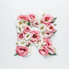 Obraz na płótnie Canvas Letter R made with flower and leaves on bright white background. Floral mother's day alphabet concept. Spring blossom, valentine or romantic font collection. Flat lay, top view.