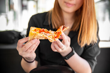 woman Hand takes a slice of meat Pizza with Mozzarella cheese, salami, Tomatoes, pepper, ham, Spices and chicken in cafe