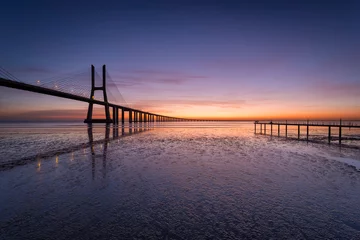 Papier Peint Lavable Pont Vasco da Gama Vasco da Gama bridge over tagus river and a pier before sunrise in Lisbon, Portugal.