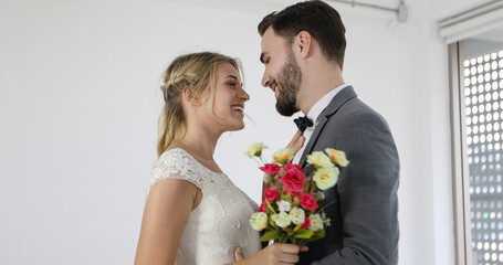 The lovers give flowers to the bride and kissed happy and couple love standing in wedding studio