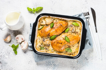Baked chicken breast with mushrooms in cream sauce on white kitchen table.