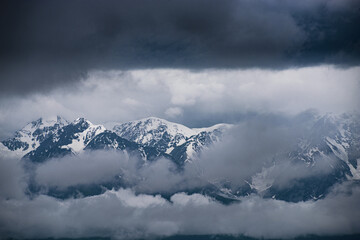 picturesque view of snow-covered mountains among clouds 