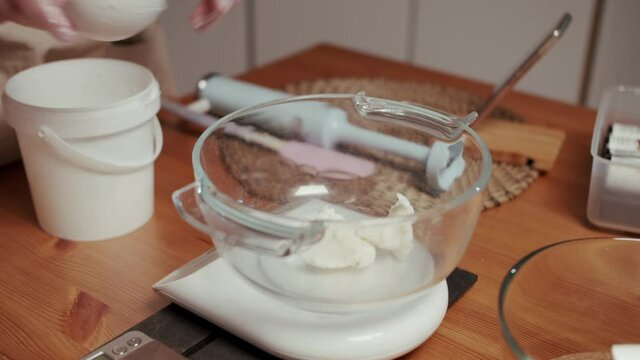 A close-up of woman's hands cutting the soap into bars on the soap-cutting machine. She puts all the bars in a row