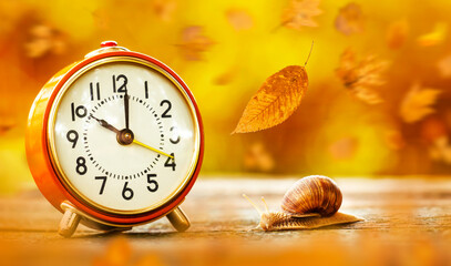 Orange alarm clock with snail and falling leaves. Daylight savings time, autumn background. © Reddogs