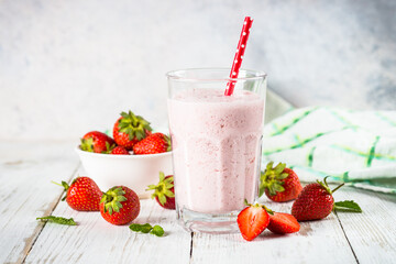 Strawberry smoothie or milkshake at white kkitchen table.