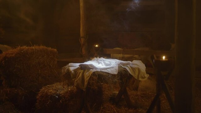 Illuminated manger with blanket in dim stable on Christmas day