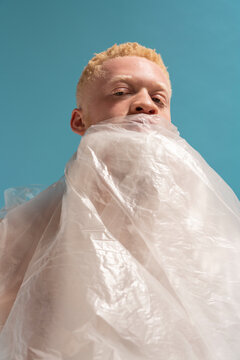 Studio portrait of albino man wrapped in plastic sheet