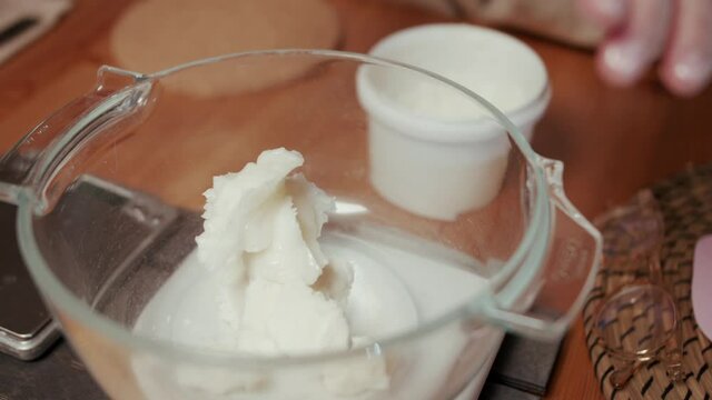 A close-up of woman's hands cutting the soap into bars on the soap-cutting machine. She puts all the bars in a row