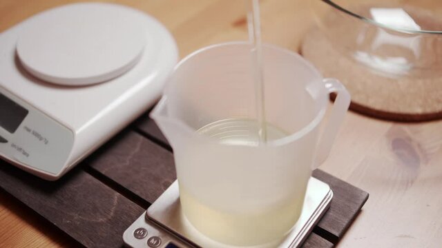 A close-up of woman's hands cutting the soap into bars on the soap-cutting machine. She puts all the bars in a row