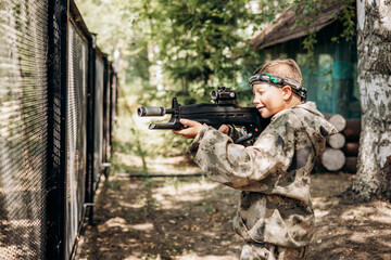 Boy looking into the optical sight a weapon. Children playing laser tag shooting game in outdoor....