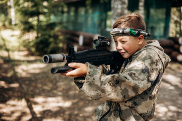 Boy looking into the optical sight a weapon. Children playing laser tag shooting game in outdoor....