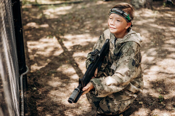 Boy with a weapon in his hand playing laser tag shooting game in outdoor. War simulation game