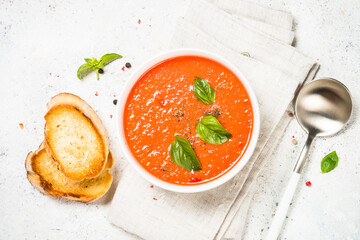 Tomato soup or gazpacho with basil. Summer cold vegan dish. Top view at white background.