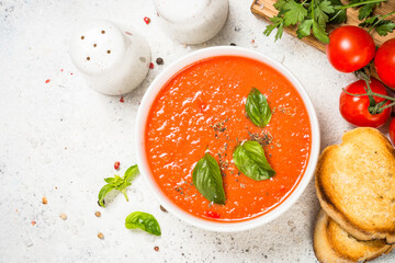 Tomato soup or gazpacho with basil. Summer cold vegan dish. Top view at white table with copy space.