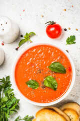Tomato soup or gazpacho with basil. Summer cold vegan dish. Top view at white background.