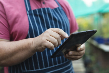 Hands of caucasian male gardener using tablet at garden centre