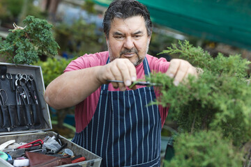Caucasian male gardener cutting trees at garden centre