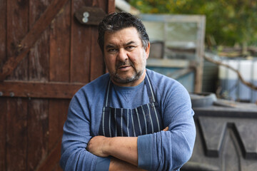 Portrait of caucasian male gardener with crossed hands looking at camera at garden centre