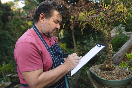 Profile of caucasian male gardener making notes at garden centre - Powered by Adobe