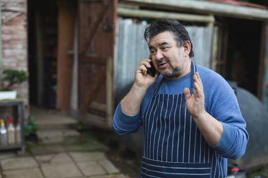 Caucasian male gardener talking by smartphone at garden centre
