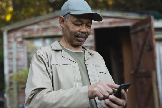 African american male gardener using smartphone at garden centre