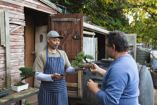Two diverse men using contactless payments at garden centre - Powered by Adobe