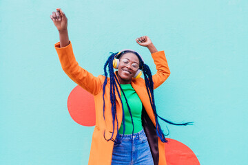 Italy, Milan, Stylish woman with headphones dancing against wall