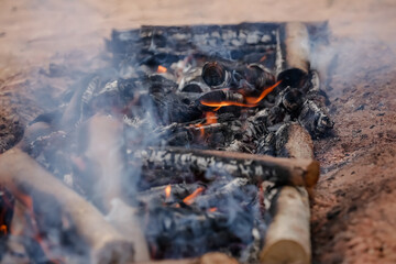 Fogo crepitando no chão, a brasa perfeita para assar carnes, espalhando um aroma irresistível pelo ar.