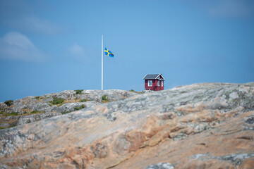 Little house on top of the island on Swedish west coast with flag pole and swedish flag.