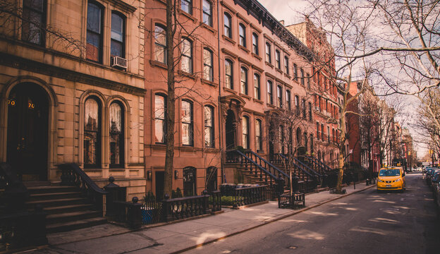 Row of old brownstone buildings along an empty sidewalk block in the Greenwich Village neighborhood of Manhattan, New York City NYC