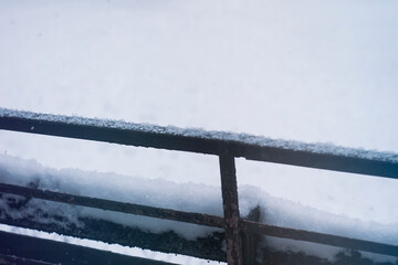 Fresh snow on the metal balcony railing
