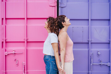happy lesbian couple smiling and holding hands over pink and purple background. Love is love. LGTBI concept