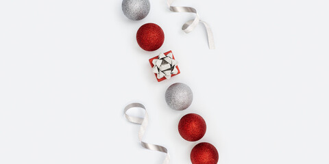Christmas composition with silver and red christmas balls and gift box with surprise on white. New Year holiday banner