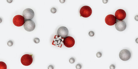 Christmas composition with silver and red christmas balls and gift box with surprise on white. New Year holiday banner
